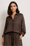 A model is shown in a four-panel collage wearing a dark brown and beige striped matching set consisting of a long-sleeve button-up shirt and wide-leg trousers. The set features a wavy, concentric stripe pattern.